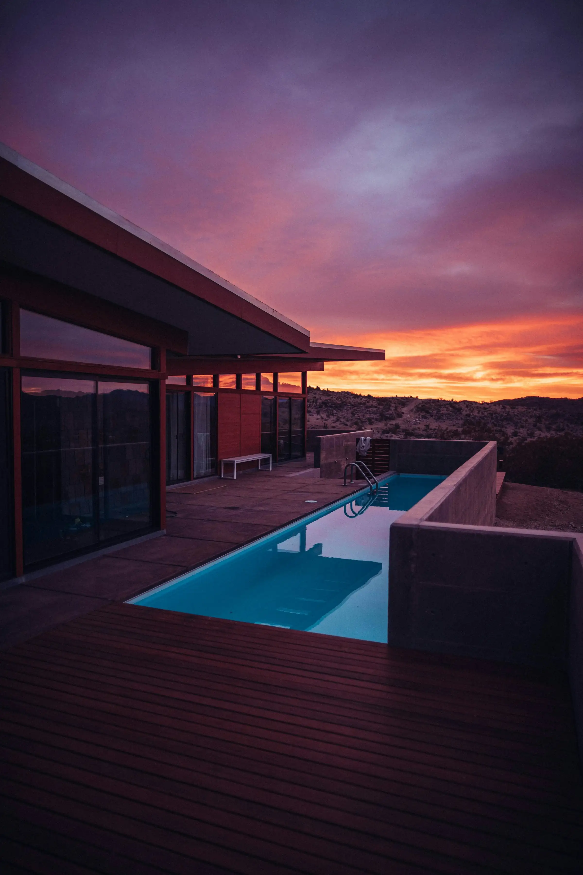 Modern hillside home with a pool at sunset